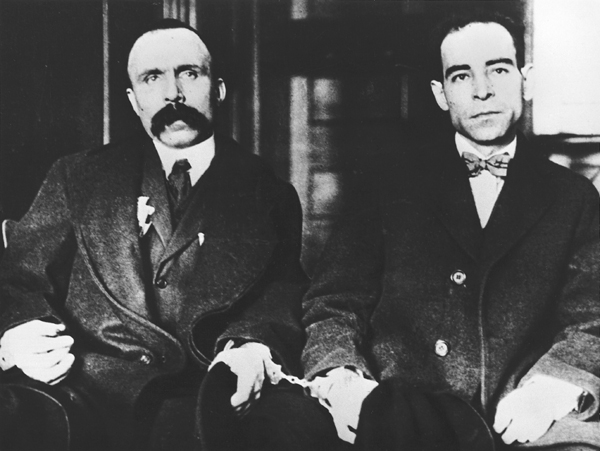 1923년의 사코와 반제티. 두 사람은 수갑이 채워져 있고 손에 모자를 들고 있다. 오른쪽의 사코는 단식투쟁 중이어서 무감각하고 멍한 눈동자에 매우 야위었다.